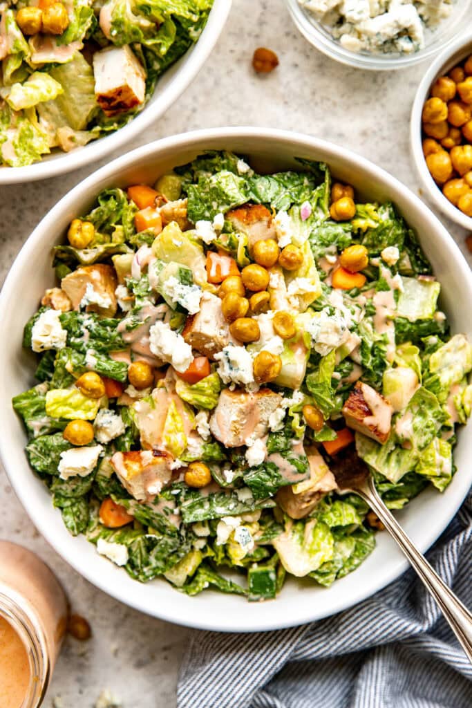 Overhead view of buffalo chicken salad topped with roasted chickpeas and chunks of blue cheese. 