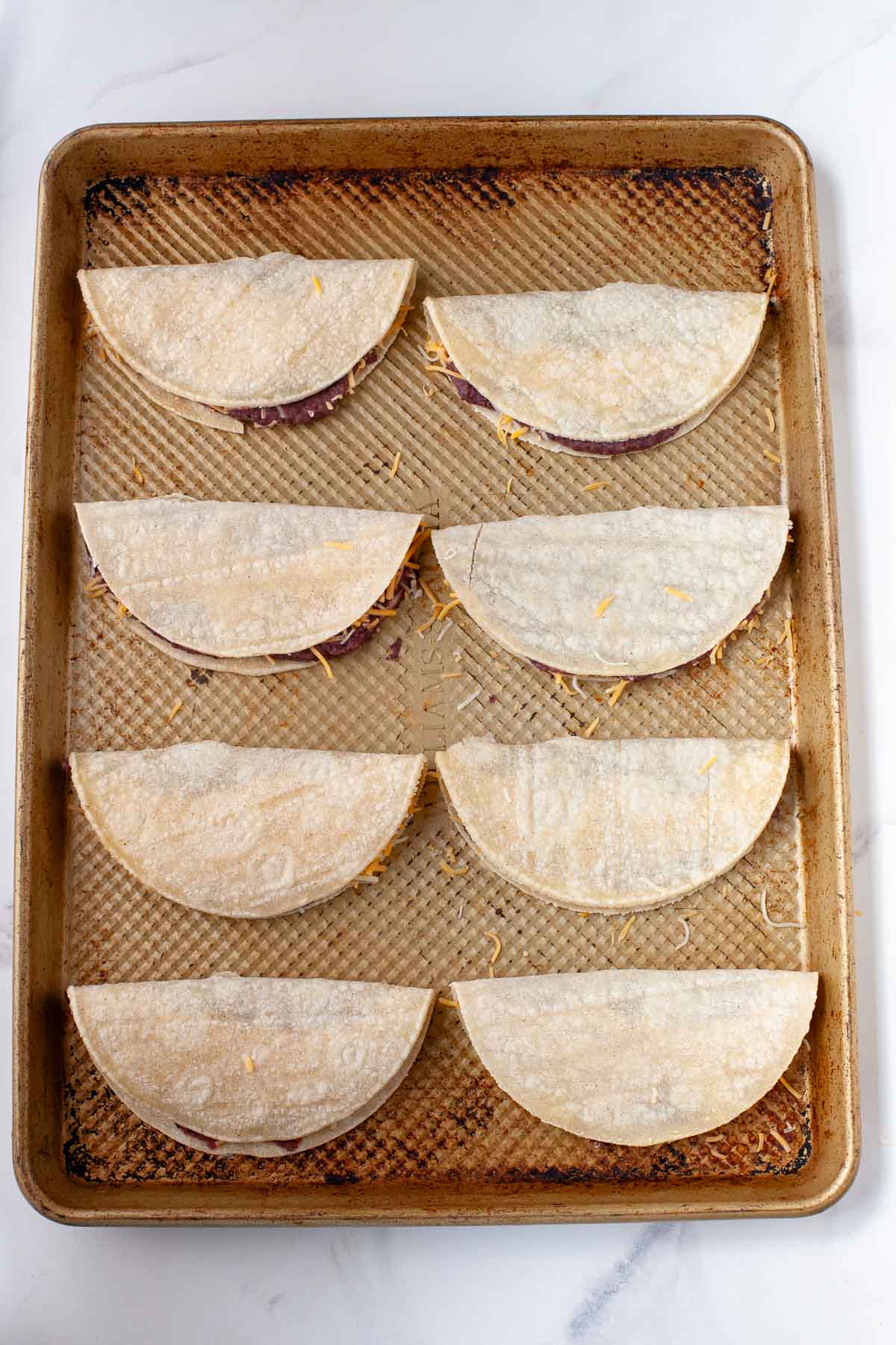 8 black bean tacos on baking sheet prior to baking 